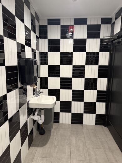 Tiled restroom with wall-mounted sink, commercial project by RDH Construction